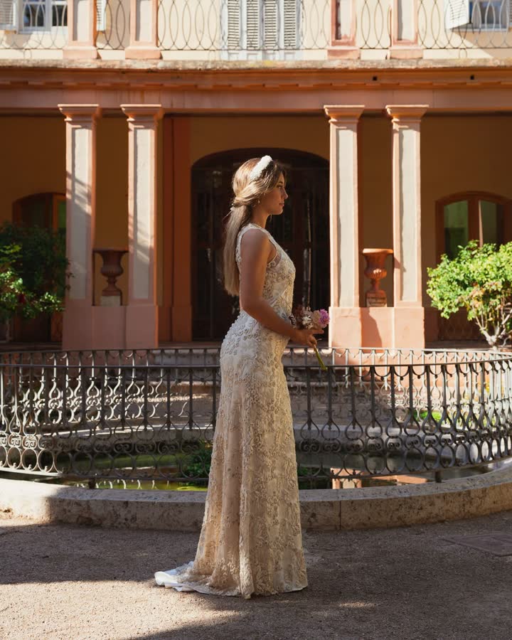 Vestido de fiesta largo bordado en tono champán junto a una balaustrada de jardín