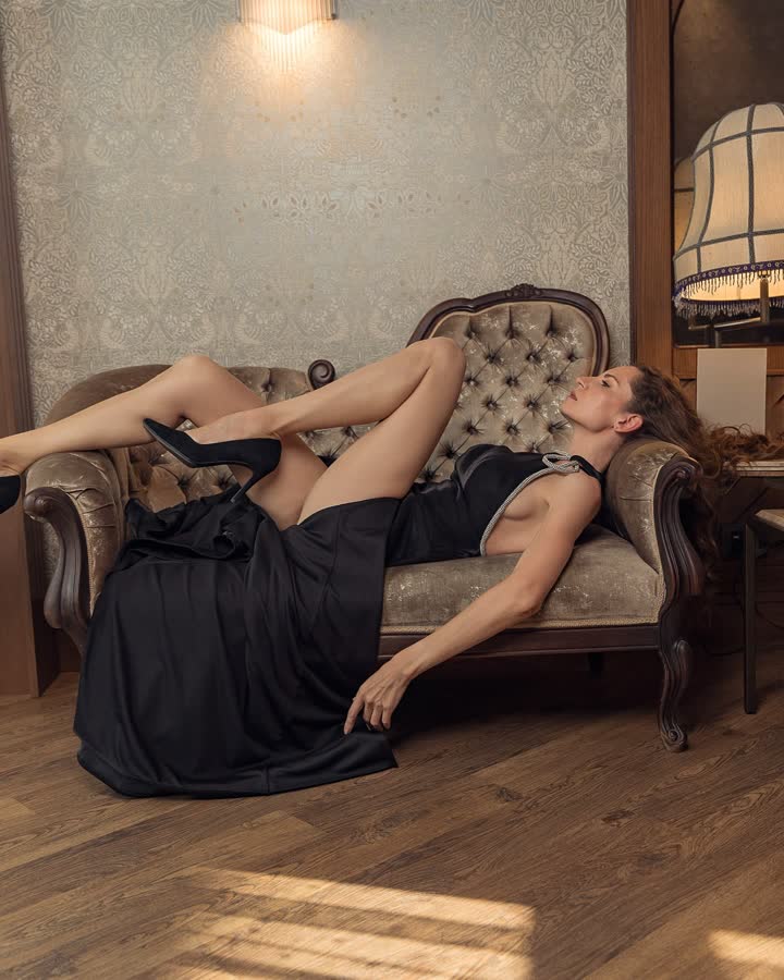 Vestido de noche negro, recostada en un sofá clásico