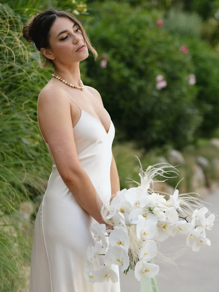 Novia con vestido lencero de seda y orquídeas blancas entre la vegetación