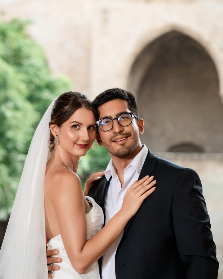 Novia con velo y vestido palabra de honor sonriendo junto al novio